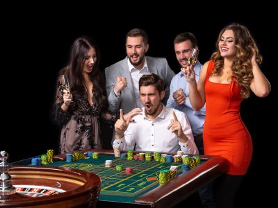 Group of young people looking excited at spinning roulette Group of young people looking excited at spinning roulette. Roulette table in a casino. Black background